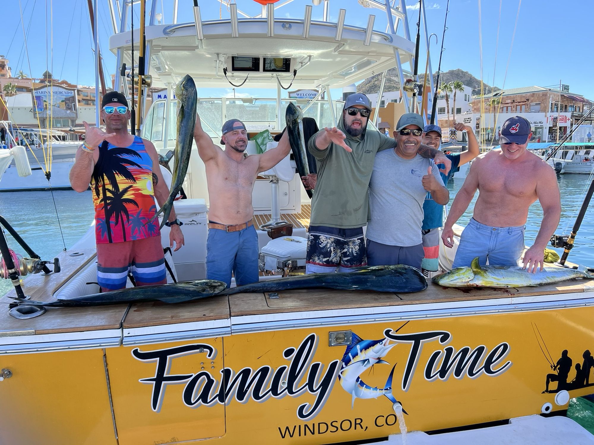Six anglers holding dorado on the stern of Family Time at the Cabo San Lucas marina